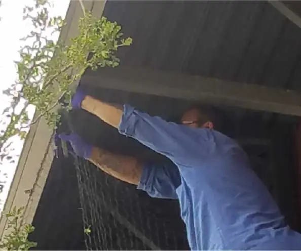 An image showing a person working on repairing or maintaining a structure, appearing to be making some adjustments or repairs.